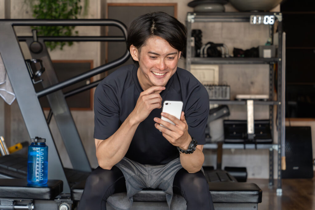 スマホでスタジオの予約をして、通いやすさを感じている男性