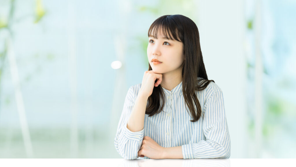 肘をついて考えごとをする女性