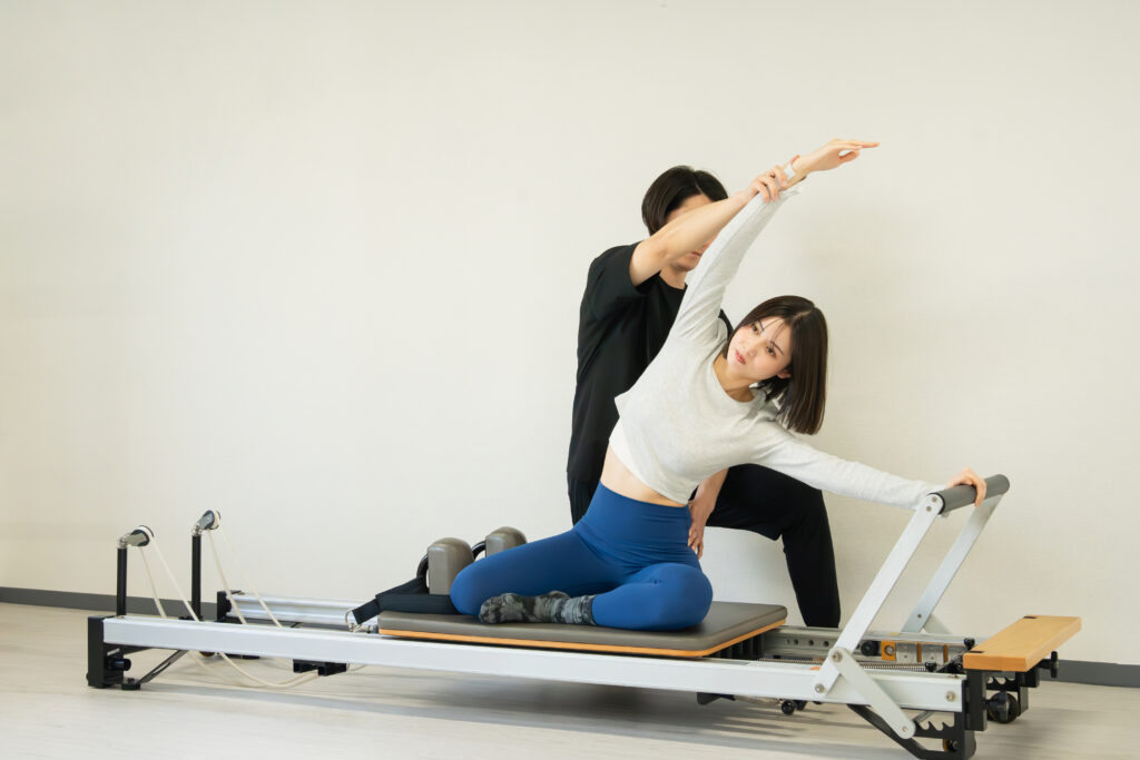 日本人女性がピラティススタジオでリフォーマーを使ったセッション
