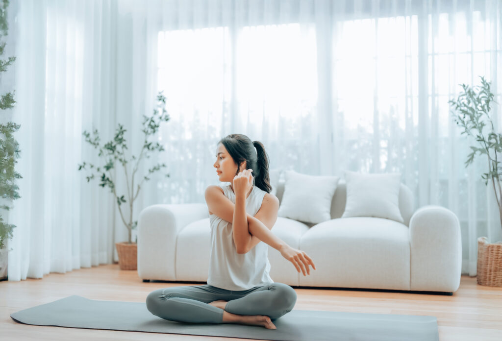 床に座って肩のストレッチをする女性