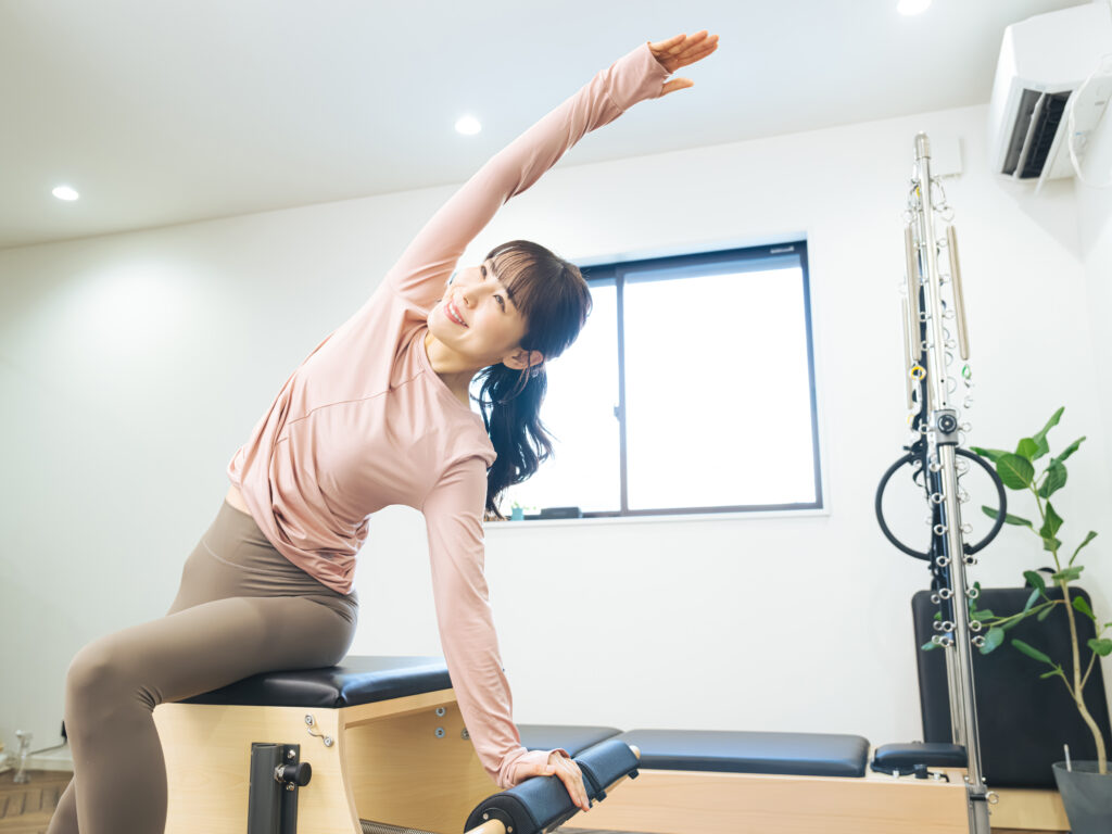 マシンピラティスのトレーニングをする笑顔の女性