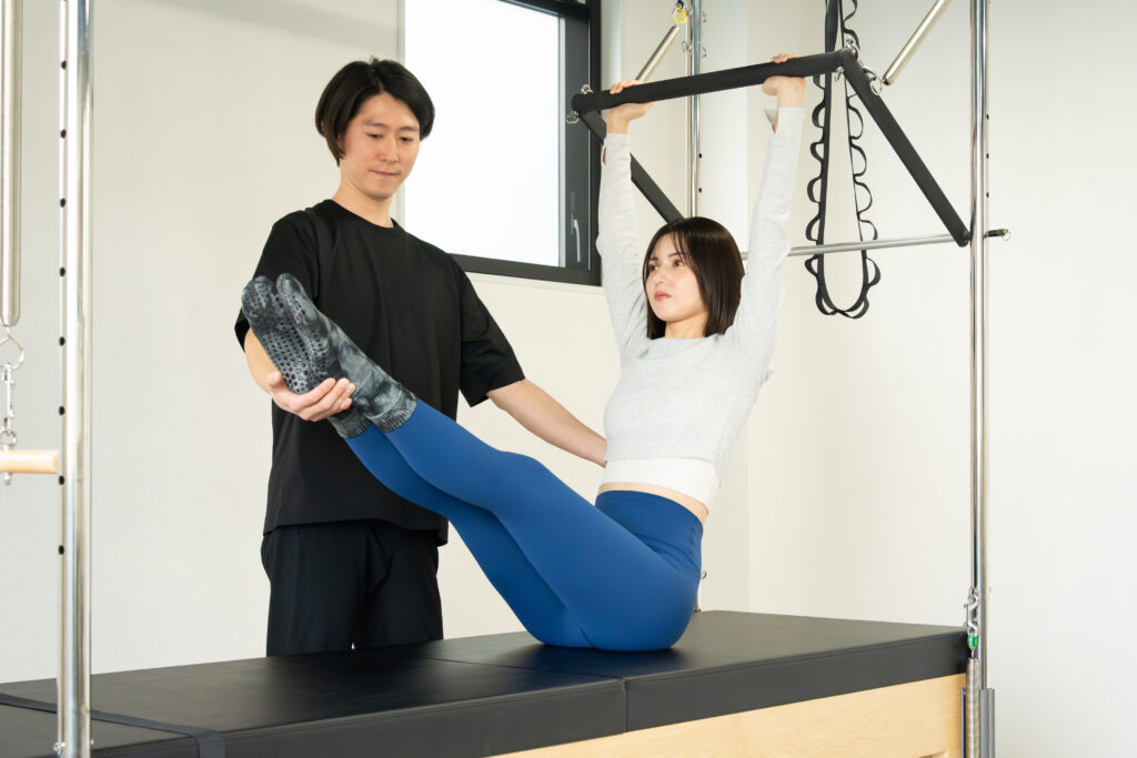 インストラクターの指導を受けてピラティスを実践する女性