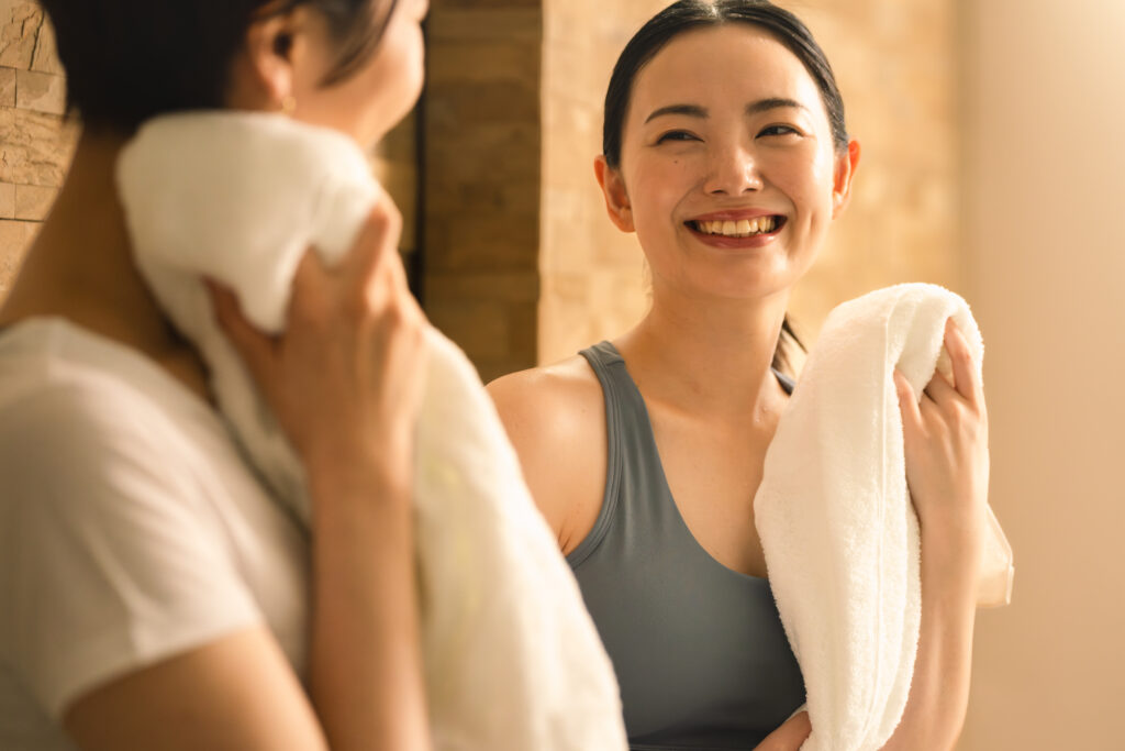 ピラティスで汗をかいた後、タオルで拭く女性