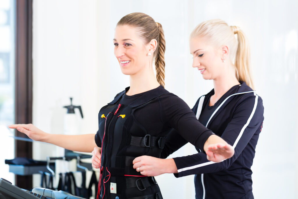 EMS電気筋肉刺激スーツを着た女性とサポートするコーチ