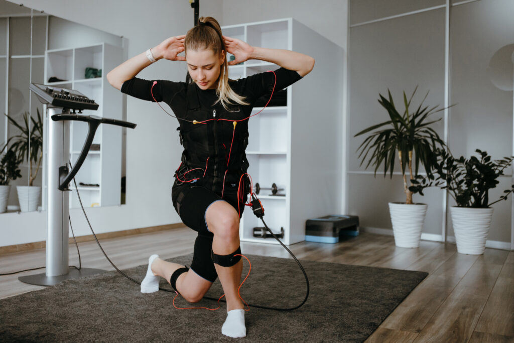 EMSスーツを着て、フロントランジをしている女性