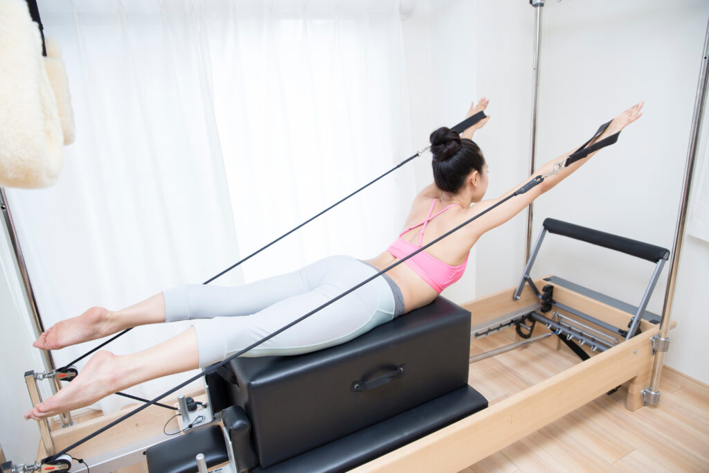 ピラティスリフォーマーを使ってエクササイズをする女性